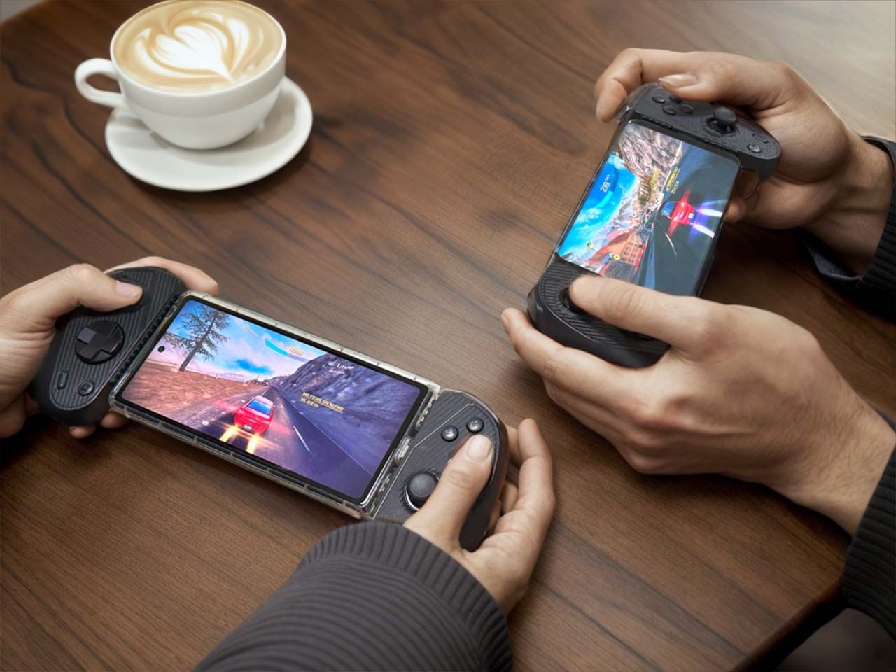 Two teenagers play Asphalt 8 with the S3 Mobile Gaming Controller on a table at a coffee shop