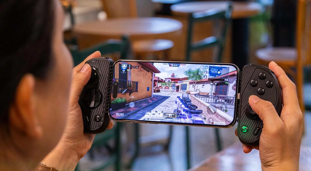 Serafim S3 controller attached to an iPhone as a user plays a fast-paced FPS mobile game.